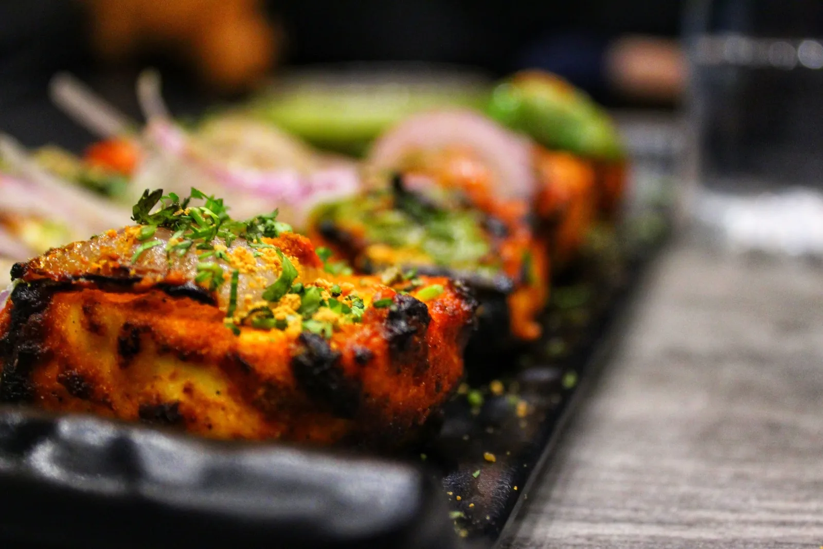 Tandoori chicken pieces on a slate board with fresh salad