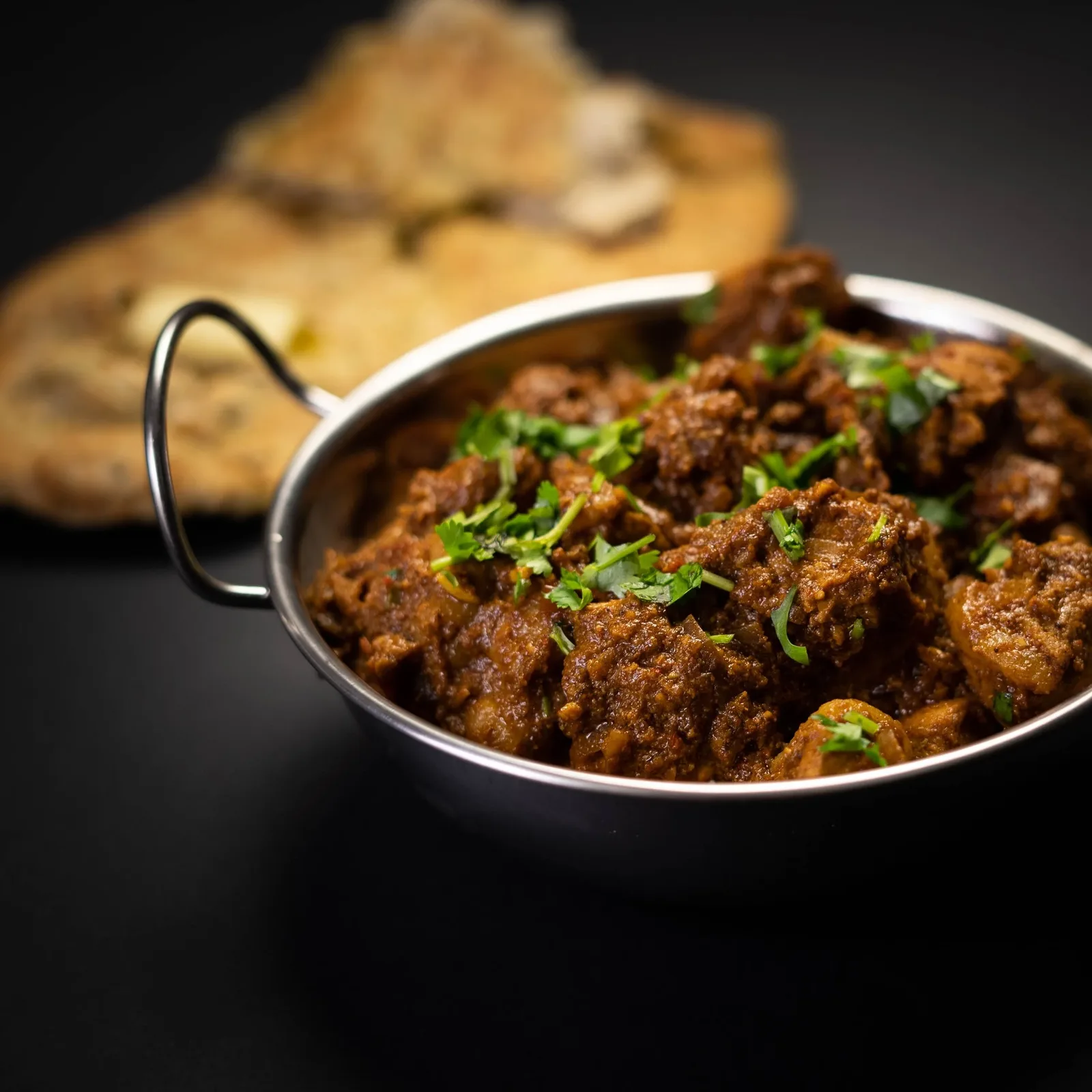 Lamb curry in a balti dish topped with fresh coriander